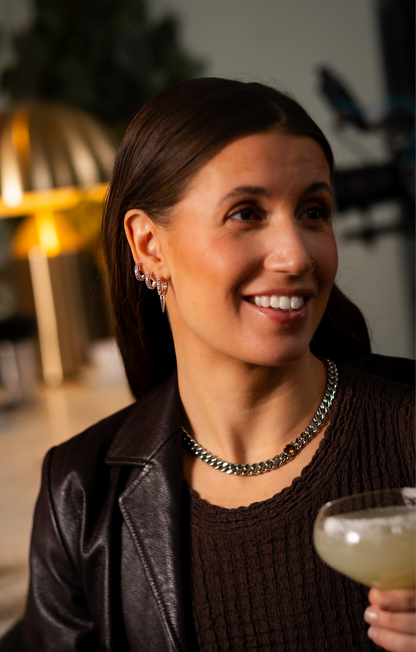 Modell bär tjockt kedjehalsband i rostfritt stål med brun kubisk zirkona-sten och brun klänning