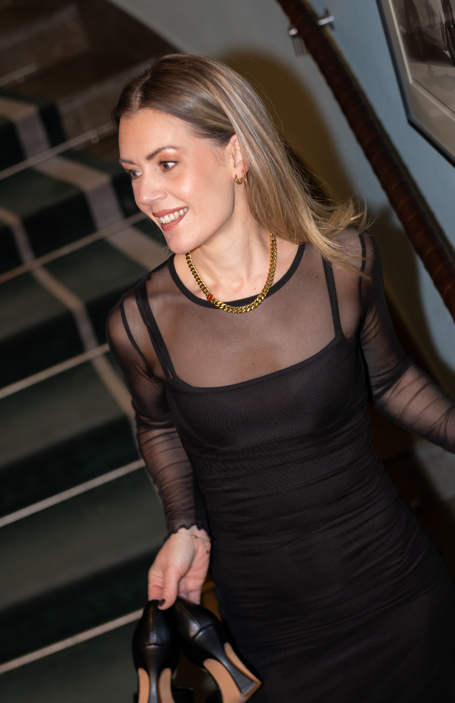 Modell bär guldhalsband med brun sten i svart klänning