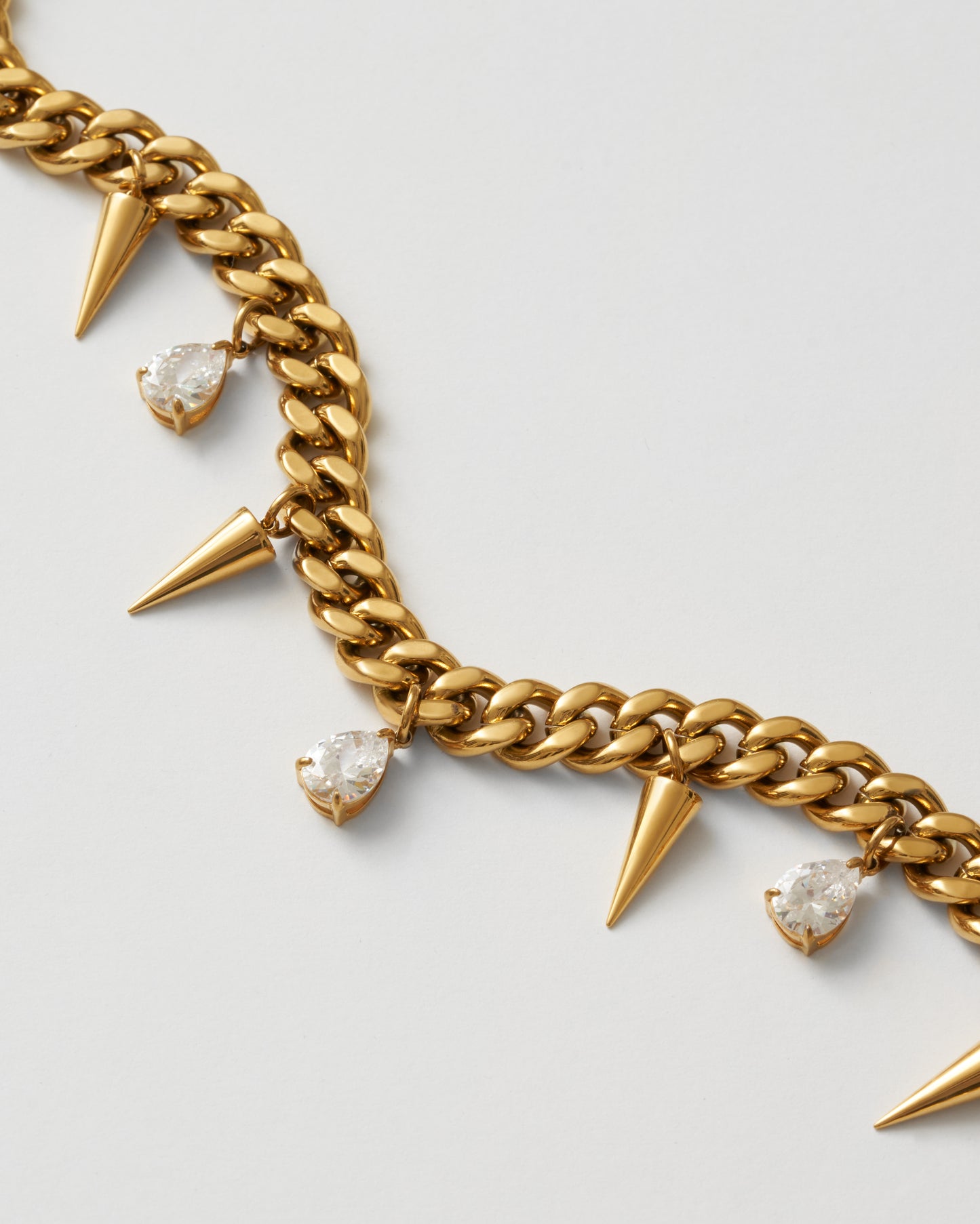 Guldhalsband med nitar och vita kubiska zirkonia-stenar fotad nära, uppifrån