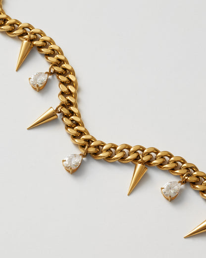 Guldhalsband med nitar och vita kubiska zirkonia-stenar fotad nära, uppifrån