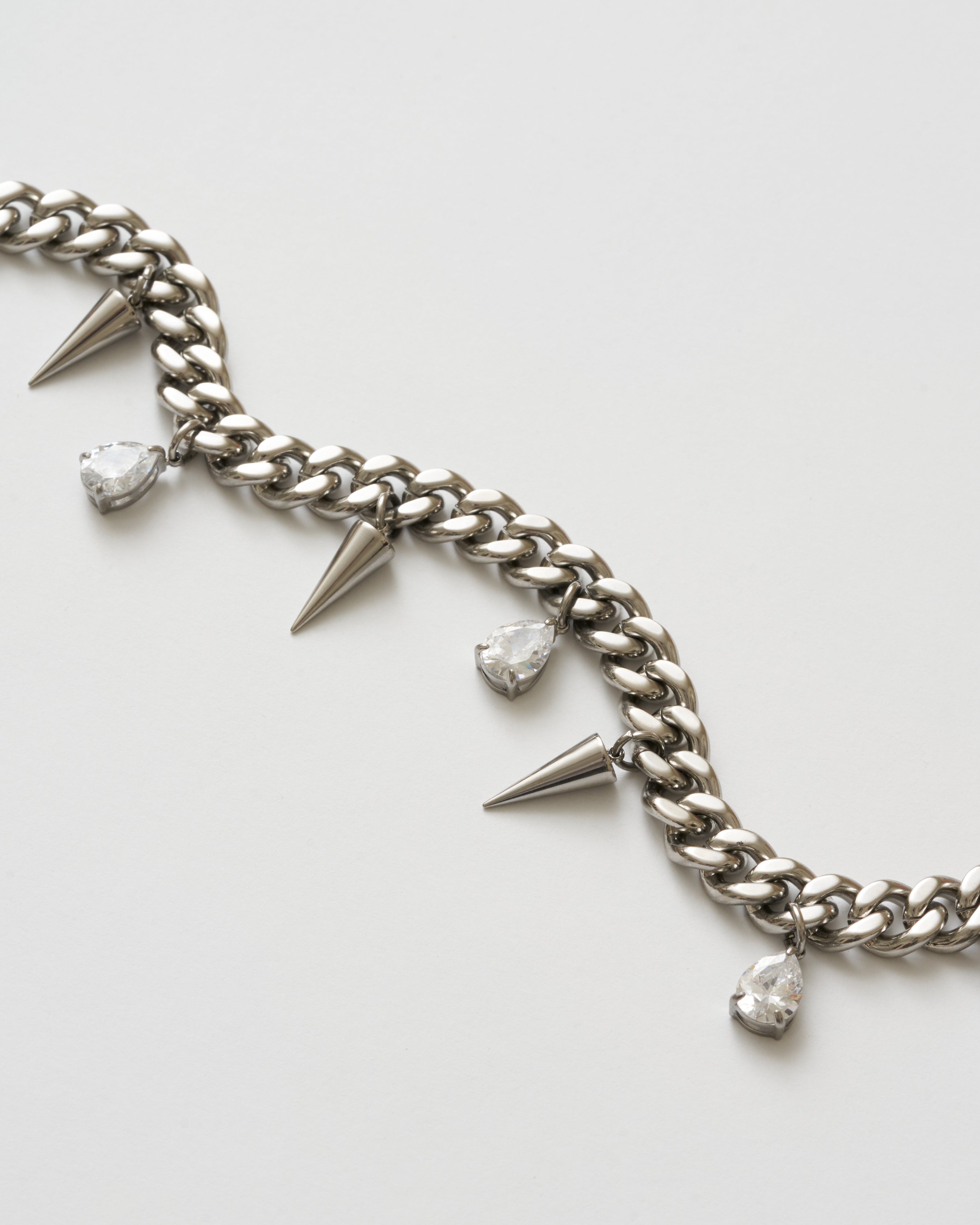 Närbild på detaljer på silverhalsband med nitar och vita kubiska zirkonia-stenar