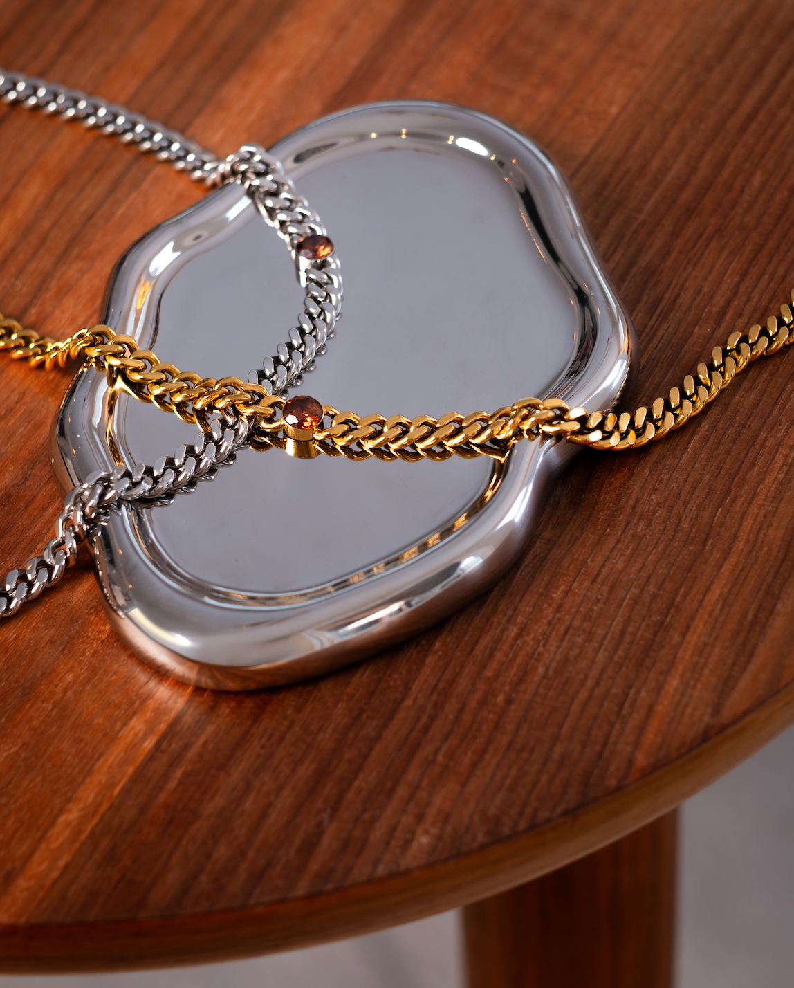 Silver- och guldfärgade kedjehalsband i rostfritt stål med asymmetriskt placerad cubic zirconia-sten