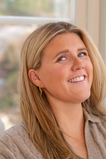 Hoop-örhängen i guld med bruna stenar och edgy siluett. Närbild på modell som skrattar i höstljus