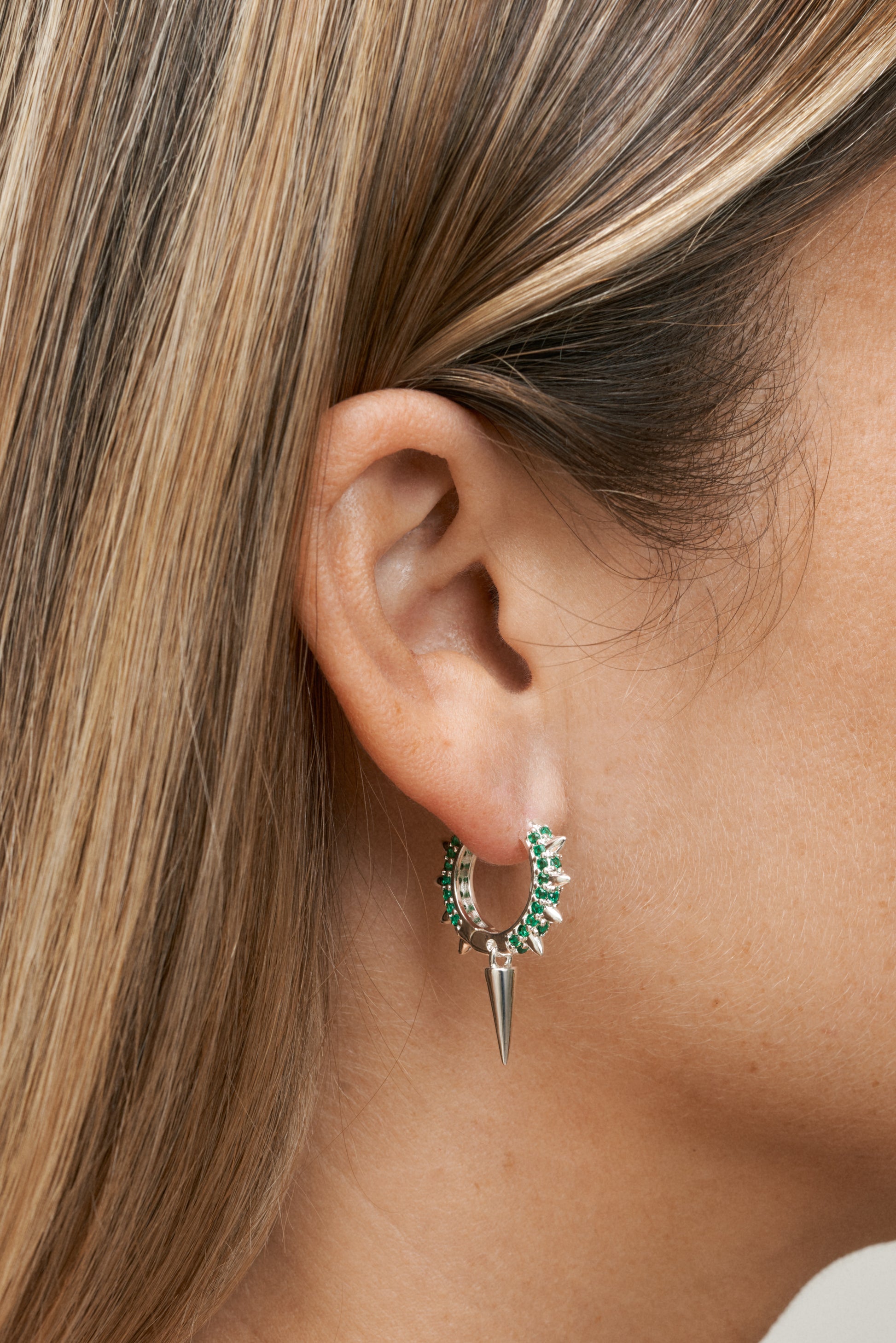 Silver hoops med gröna stenar, konformad detalj och kall glans – Studio W. Närbild på öra.