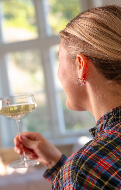Silver hoops med röda zirkoner och spetsig hänge – djärv men elegant stil. På öra i festlig mingelmiljö