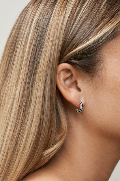 Sterling silverpläterade hoop-örhängen med svarta zirkoner. Närbild på öra