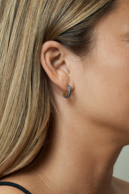 18k guldpläterade hoops med blå zirkonstenar – Studio W. Närbild på öra