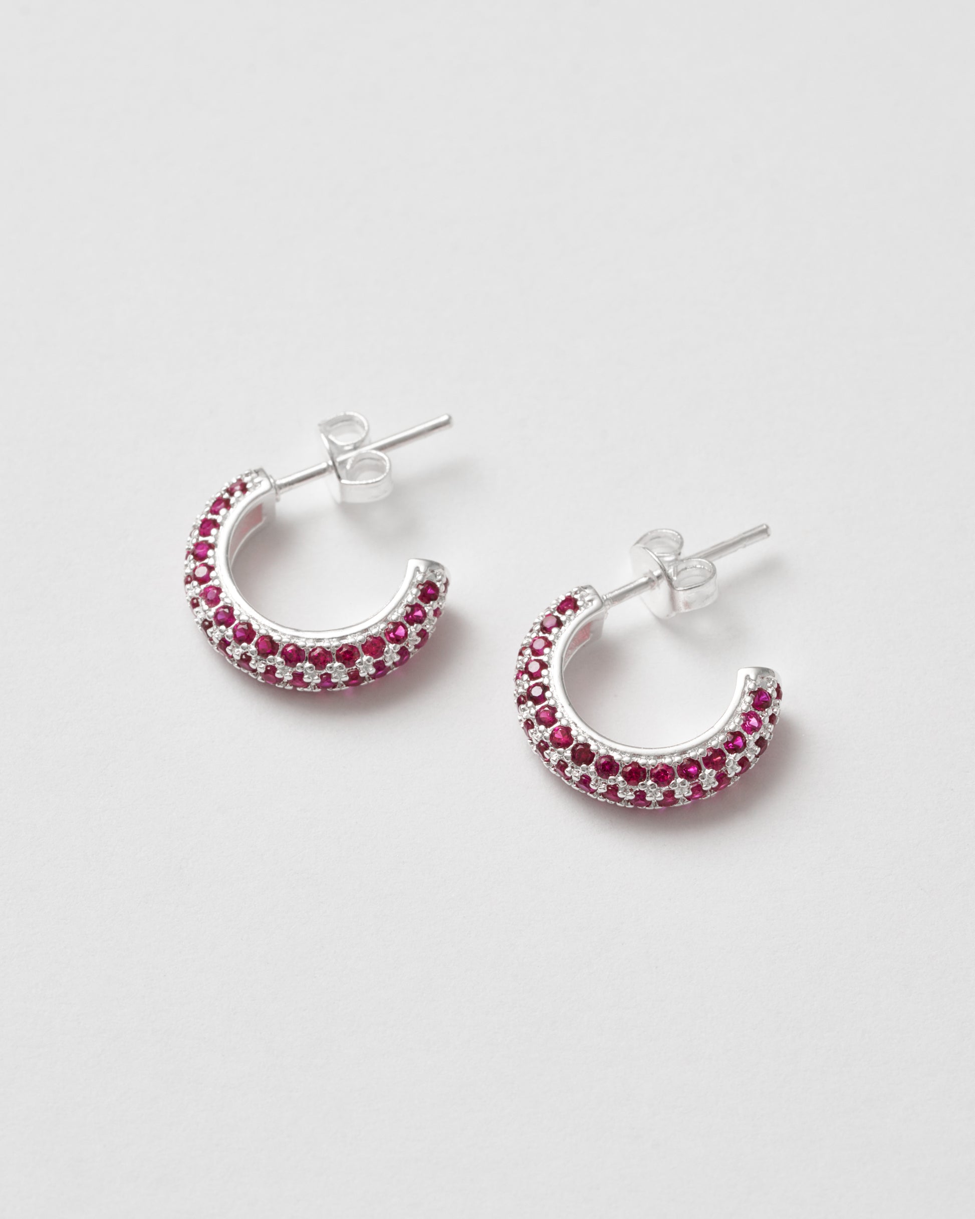 Små silver hoops med röda stenar, diskret men färgstark accent – Studio W